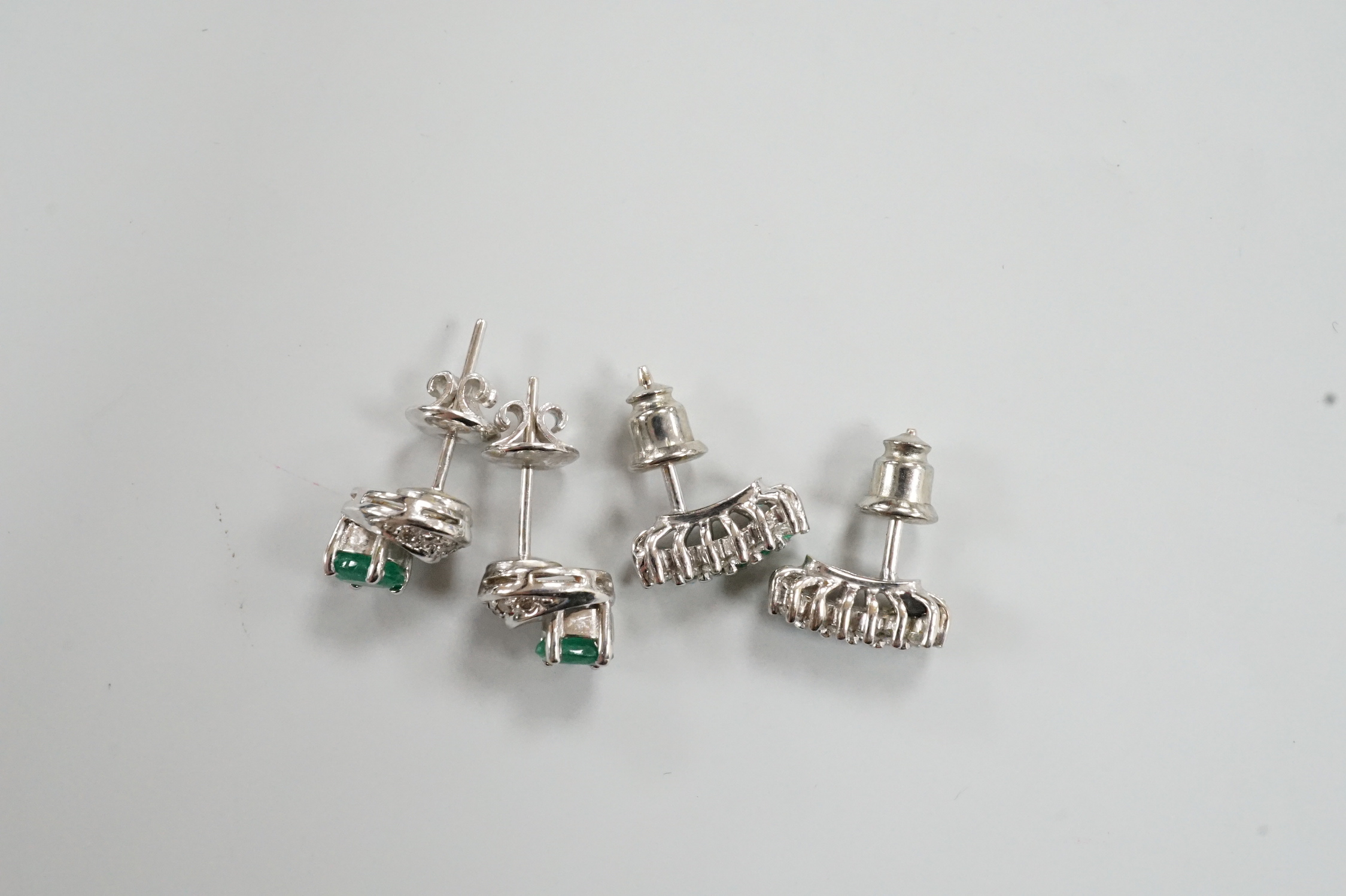 Two moderns pairs of emerald and diamond set ear studs, including white metal two row and 14k oval cut single stone and diamond chip, 7mm, gross weight 5.6 grams.